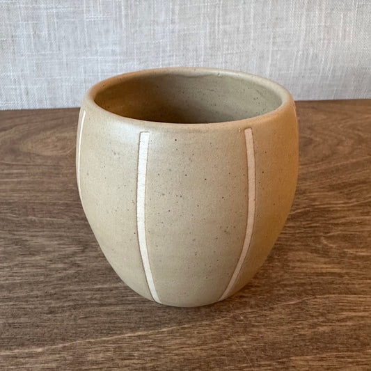 Ceramic pot with a white stripe on a wooden surface