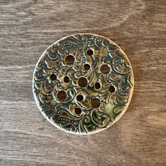 Decorative ceramic disc with intricate patterns on a wooden surface