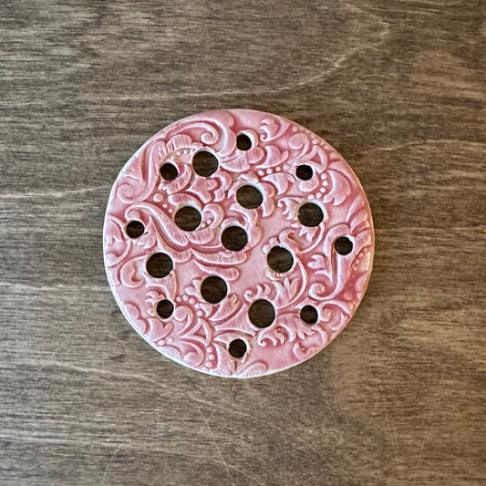 Pink decorative object with intricate patterns on a wooden surface