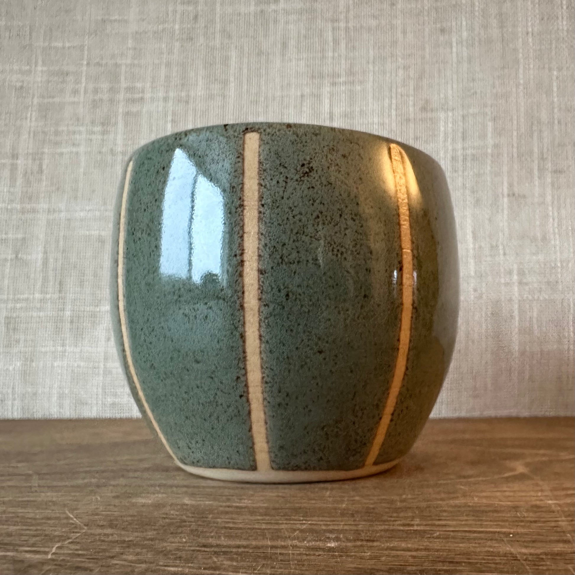 Ceramic pot with a textured surface on a wooden surface and textured wall background