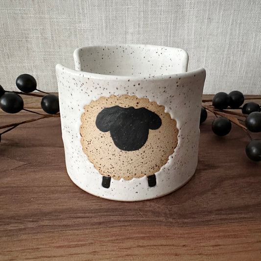 Ceramic mug with a sheep design on a wooden surface