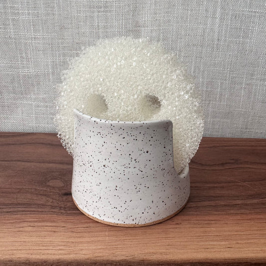 Speckled ceramic planter with a textured white cover on a wooden surface.
